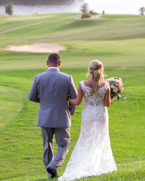 A bride and groom walking across the golf course.